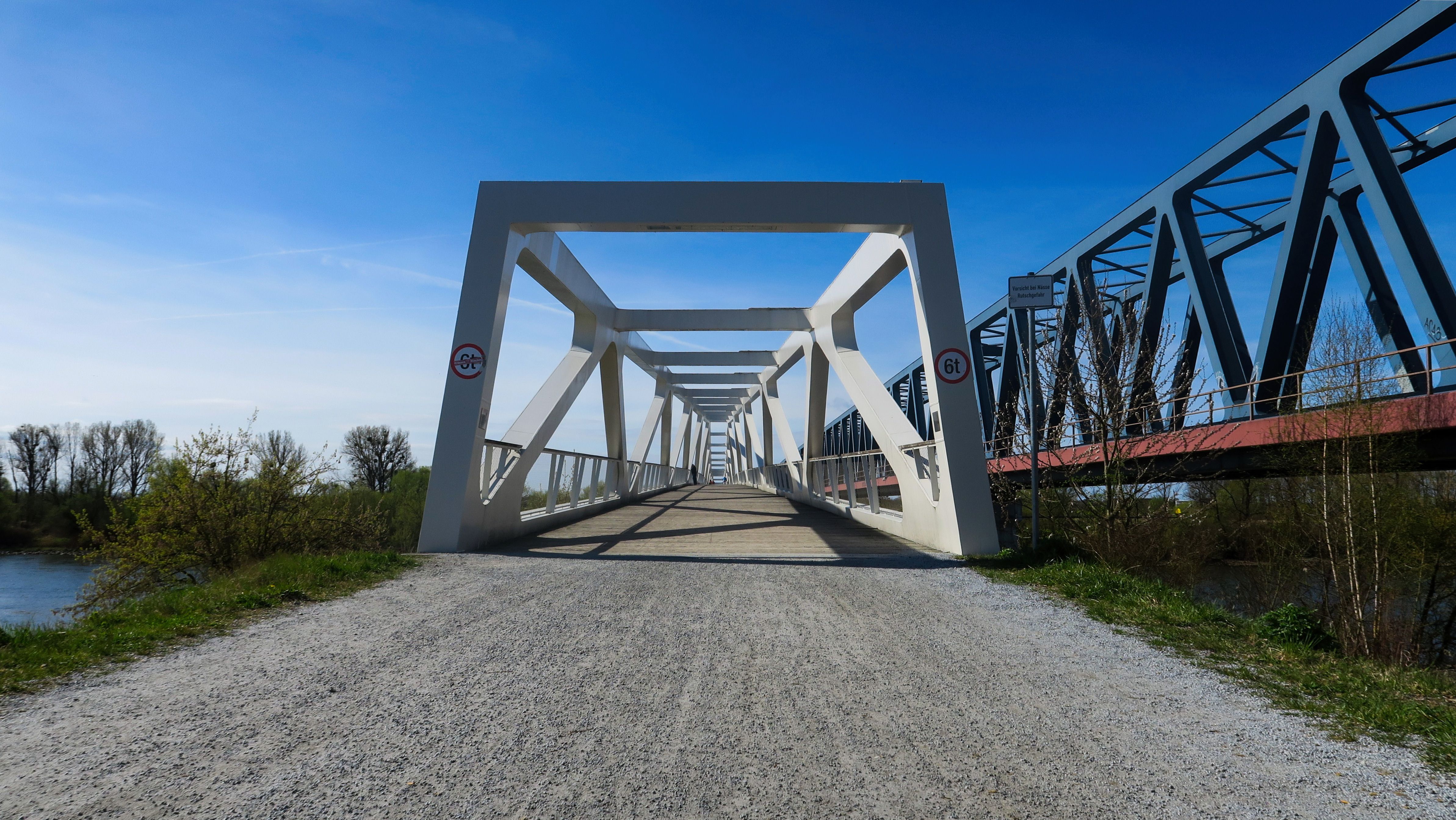 Fußgängerbrücke und Bahnbrücke rechts davon strahlend blauer Himmel